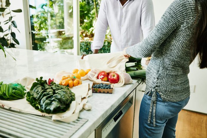 Couple Organizing Fresh Organic Vegetable And Fruit On Kitchen Counter After Shopping