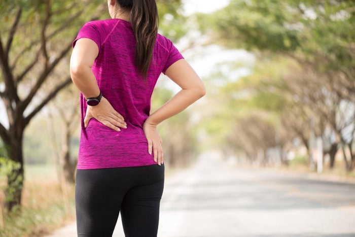hip pain running | woman clutching painful hip while running