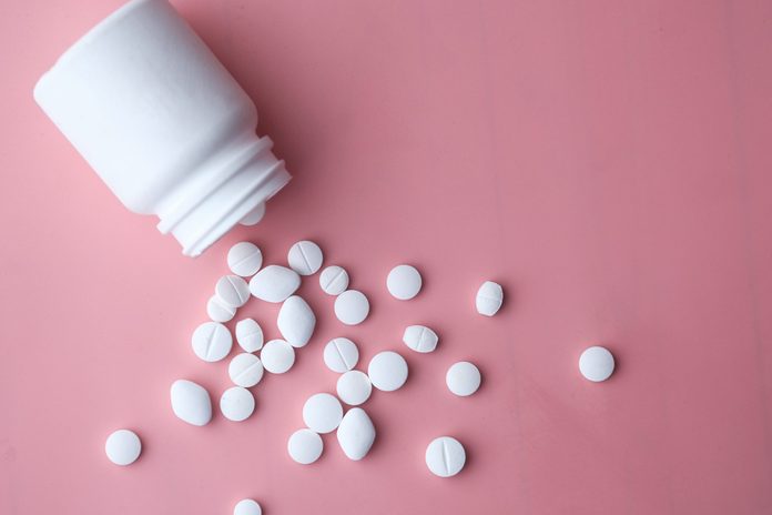 biotin vs collagen | White Pills Spilling From Bottle On Pink