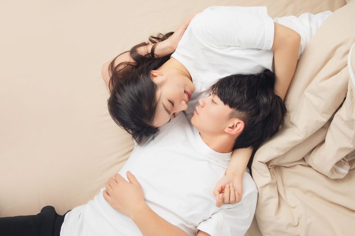how to spice up your sex life | A,young,asian,couple,is,lying,in,bed,,looking,at