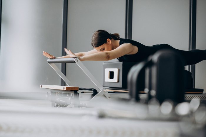 pilates reformer | woman using a pilates reformer at the gym