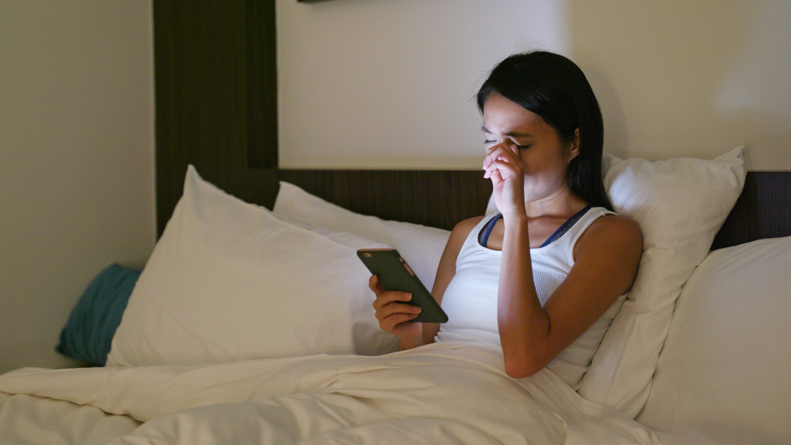 what is dry eye | woman rubbing her eyes while using cellphone in bed
