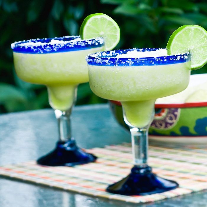 how to make frozen drinks Two frozen lime margaritas with chips and salsa in the background.