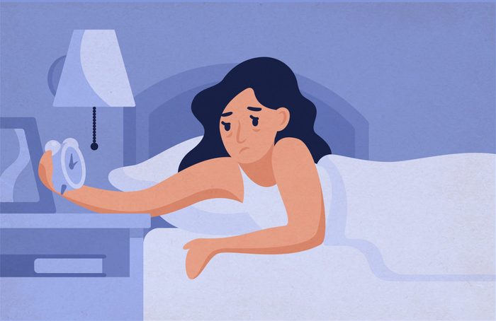 Sleepy,woman,lying,on,bed,and,looking,at,alarm,clock