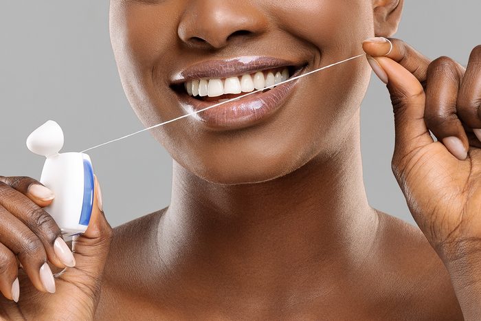 Tooth,care.,attractive,afro,woman,using,dental,floss,and,smiling