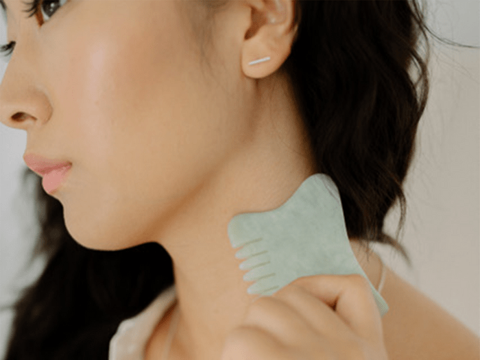 gua sha tools in Canada | image of someone using a jade comb gua sha tool on their neck