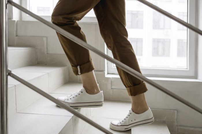 how many steps should you walk a day? | Woman In White Sneakers And Khaki Trousers Goes Upstairs White Staircase In Apartment Building