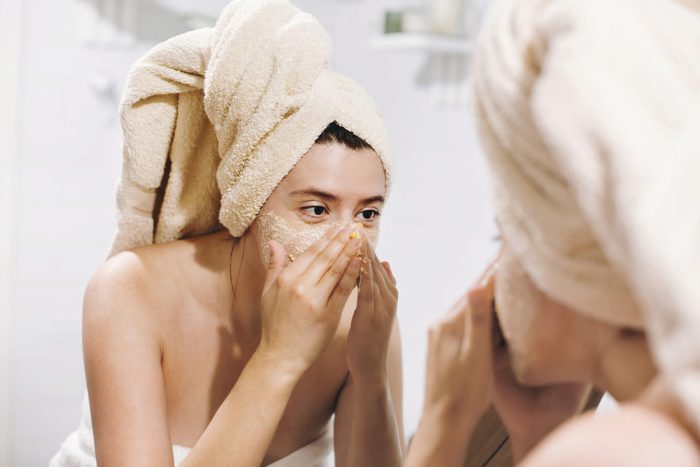 over exfoliated skin | woman exfoliating skin in mirror