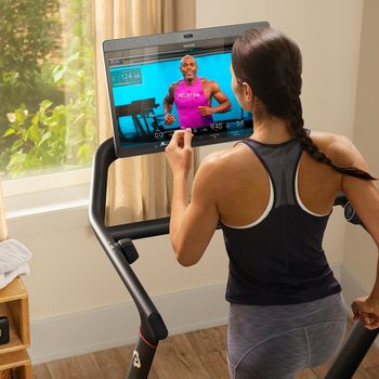 Peloton Treadmill Canada: photo of a woman on the Peloton Tread in her home during a class