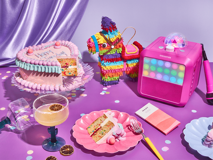 fun party goods like a cake, pinata and candy on a purple backdrop | Small Wins Products