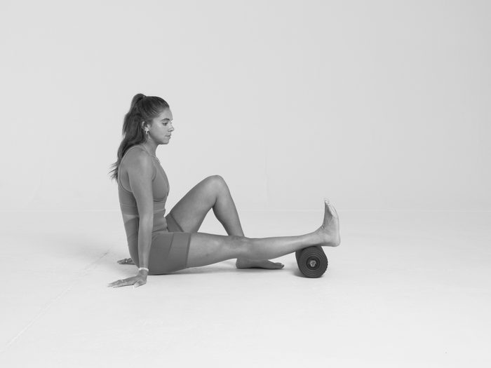 benefits of foam rolling | black and white image of woman foam rolling her calves