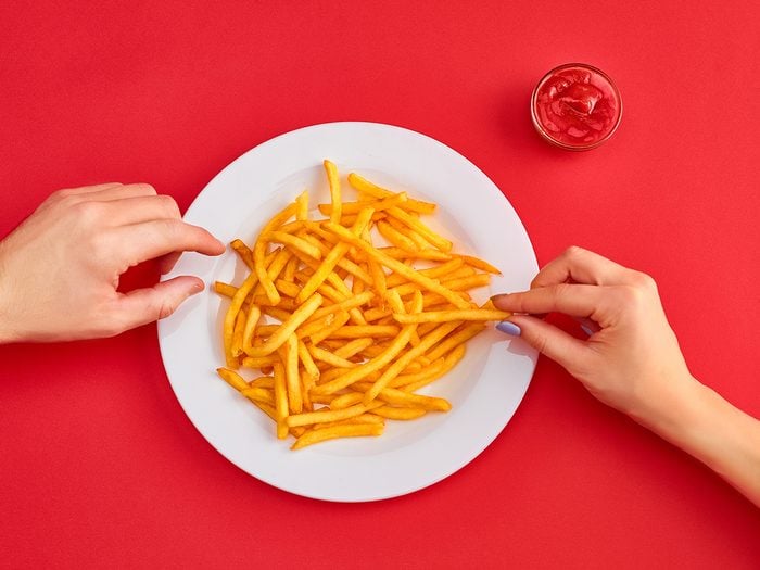 Young,woman,eating,french,fries,potato,with,ketchup,in,a